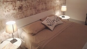 A bedroom with a bed, two bedside lamps, and a decorative pillow. - Camere Mazzini 49 (Sansepolcro)