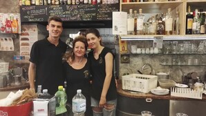 A bar area with a chalkboard menu, bottles, and glasses on shelves. - Camere Mazzini 49 (Sansepolcro)