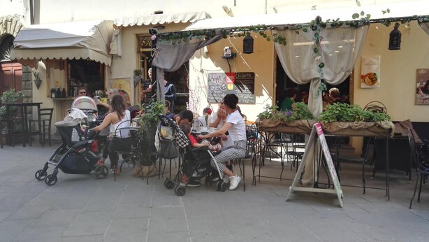 An outdoor café with tables and chairs, some with umbrellas. - Camere Mazzini 49 (Sansepolcro)