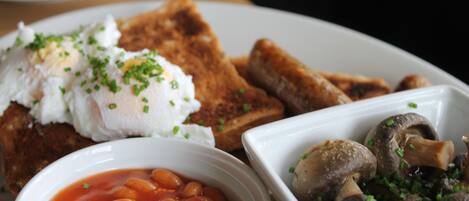 A plate with toast, poached eggs, beans, and mushrooms.
