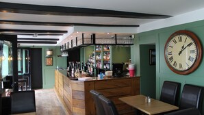Un ristorante con zona bar, arredi in legno e un grande orologio a parete.