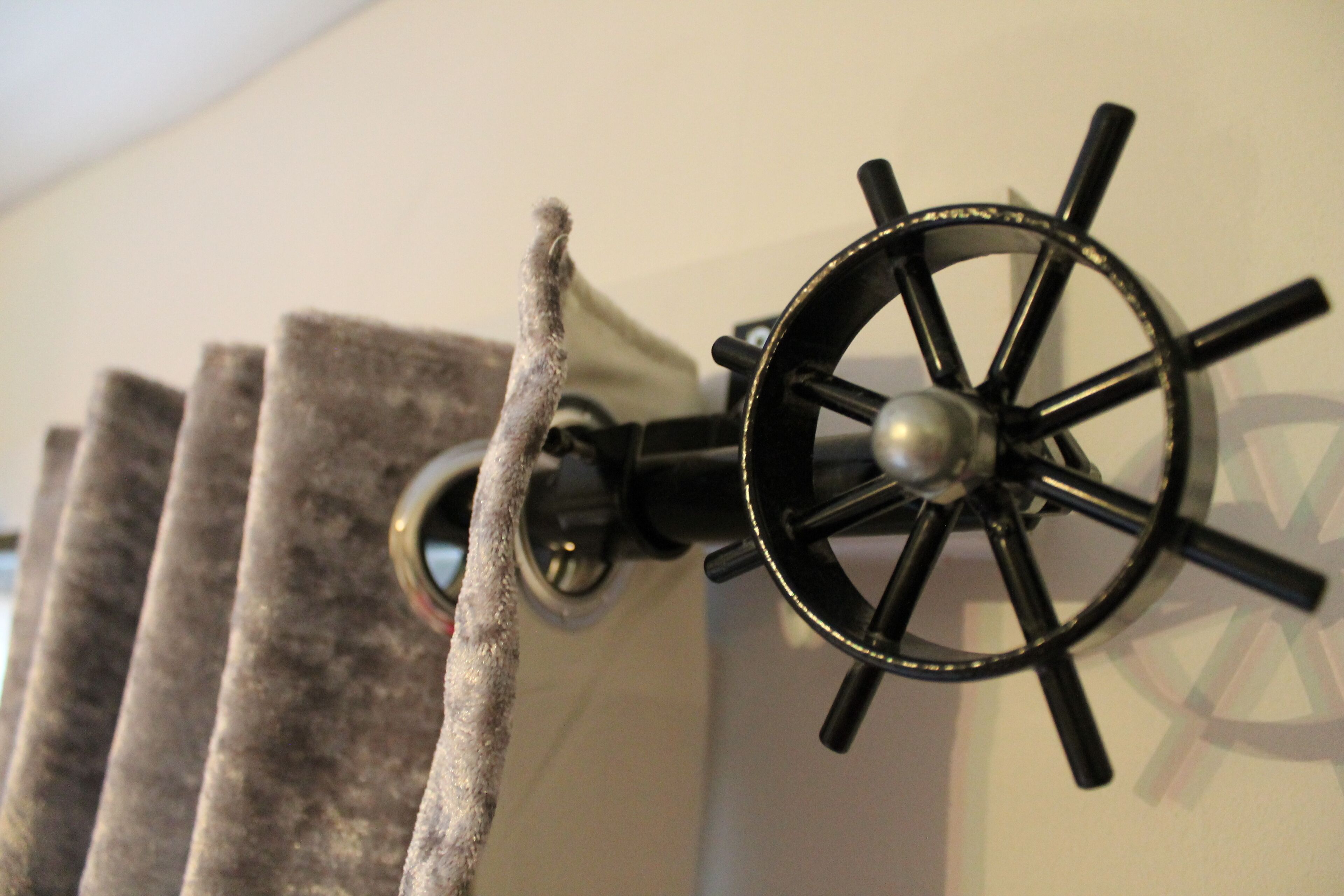 A wall-mounted ship's wheel light fixture with a textured wall behind it.