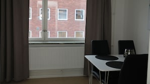 A room with a window, a table with chairs, and a radiator. - Fastliving Apartment Hotel (Vasteras)