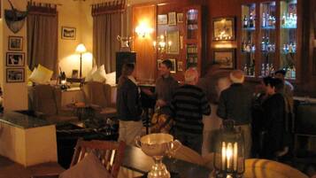 Zona de bar con detalles de madera, un trofeo sobre una mesa y una barra repleta de botellas.