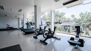 A gym with stationary bikes, a rowing machine, and a bench.