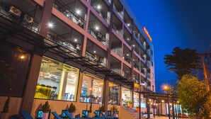 A multi-story hotel with outdoor seating and a pool.