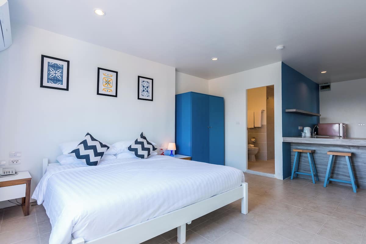 Une chambre moderne avec un lit, une table de chevet et une vue sur la cuisine.