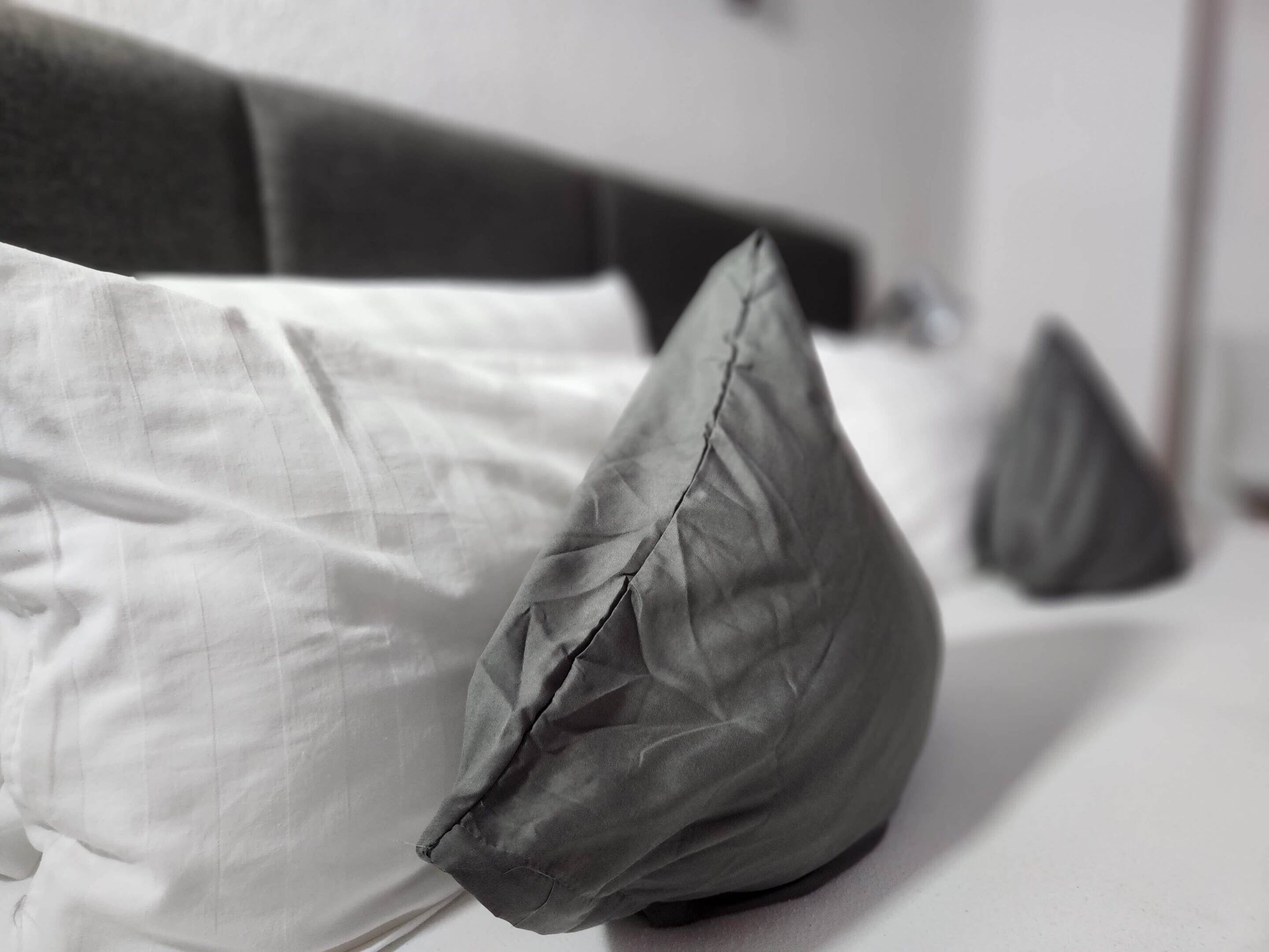 A bed with white bedding and two gray pillows.