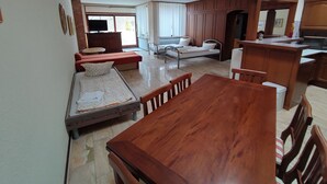 A spacious living area with a wooden dining table, a sofa, and a small kitchenette. - Hotel Schiff (Rastatt)