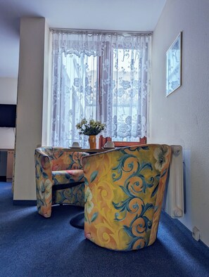 Una habitación con un sofá de curvas y estampado floral, y una mesita con un jarrón de flores.