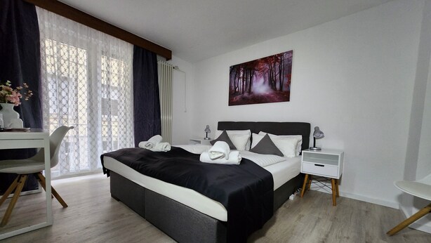 A neatly arranged bedroom with a bed, bedside tables, a desk, and a chair. - Hotel Schiff (Rastatt)