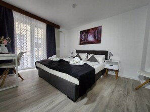 A hotel room with a bed, bedside tables, a desk, and a chair. - Hotel Schiff (Rastatt)