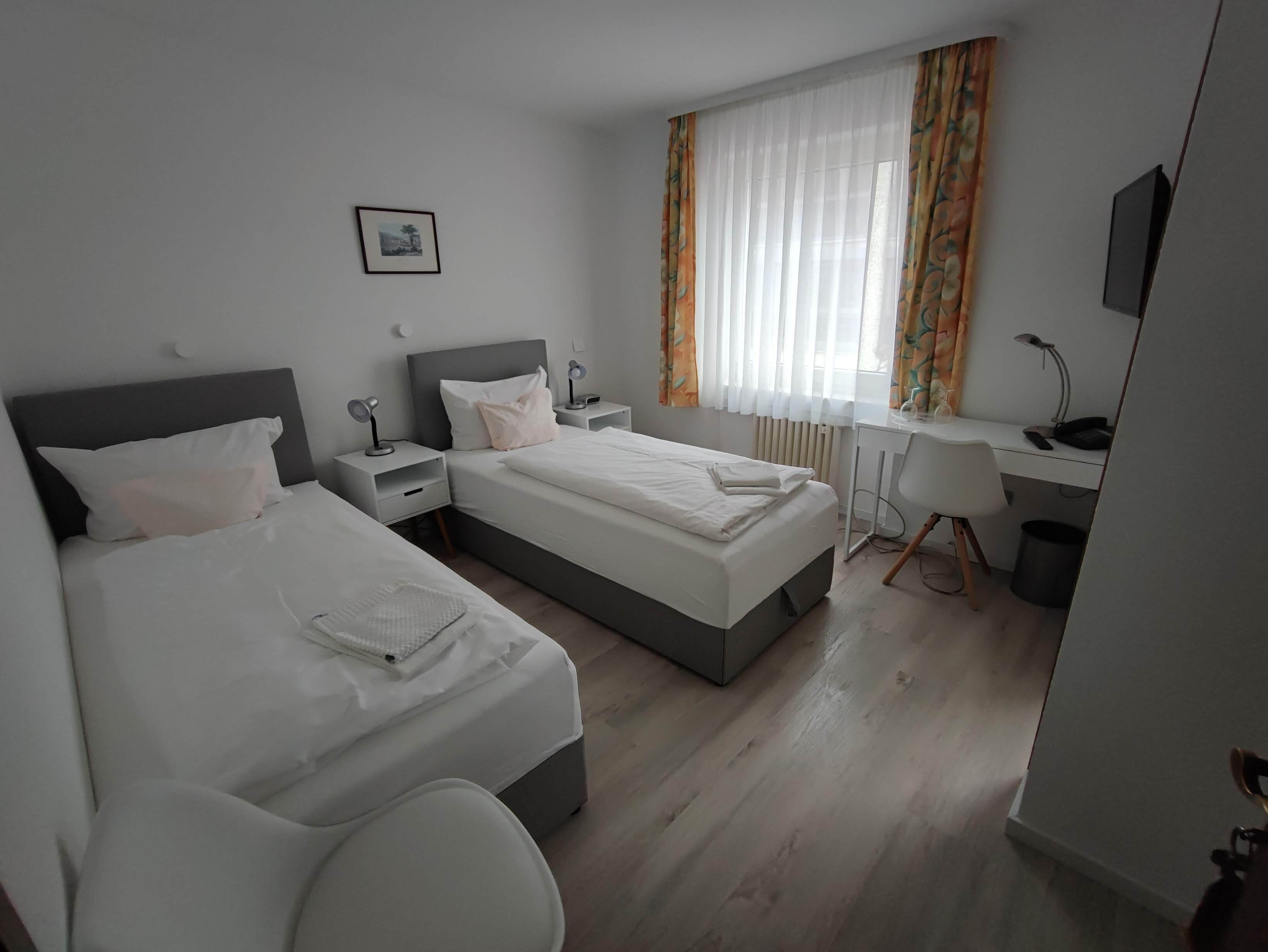 A hotel room with two beds, a desk, and a chair.