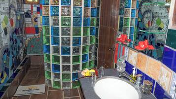 A bathroom with a mosaic tile wall, a wooden door, a sink, and a glass shower enclosure.