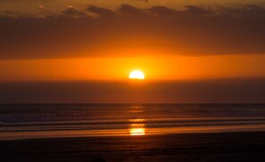 A sunset over the ocean with the sun partially visible above the horizon. - Paradise Lodge (Barú)