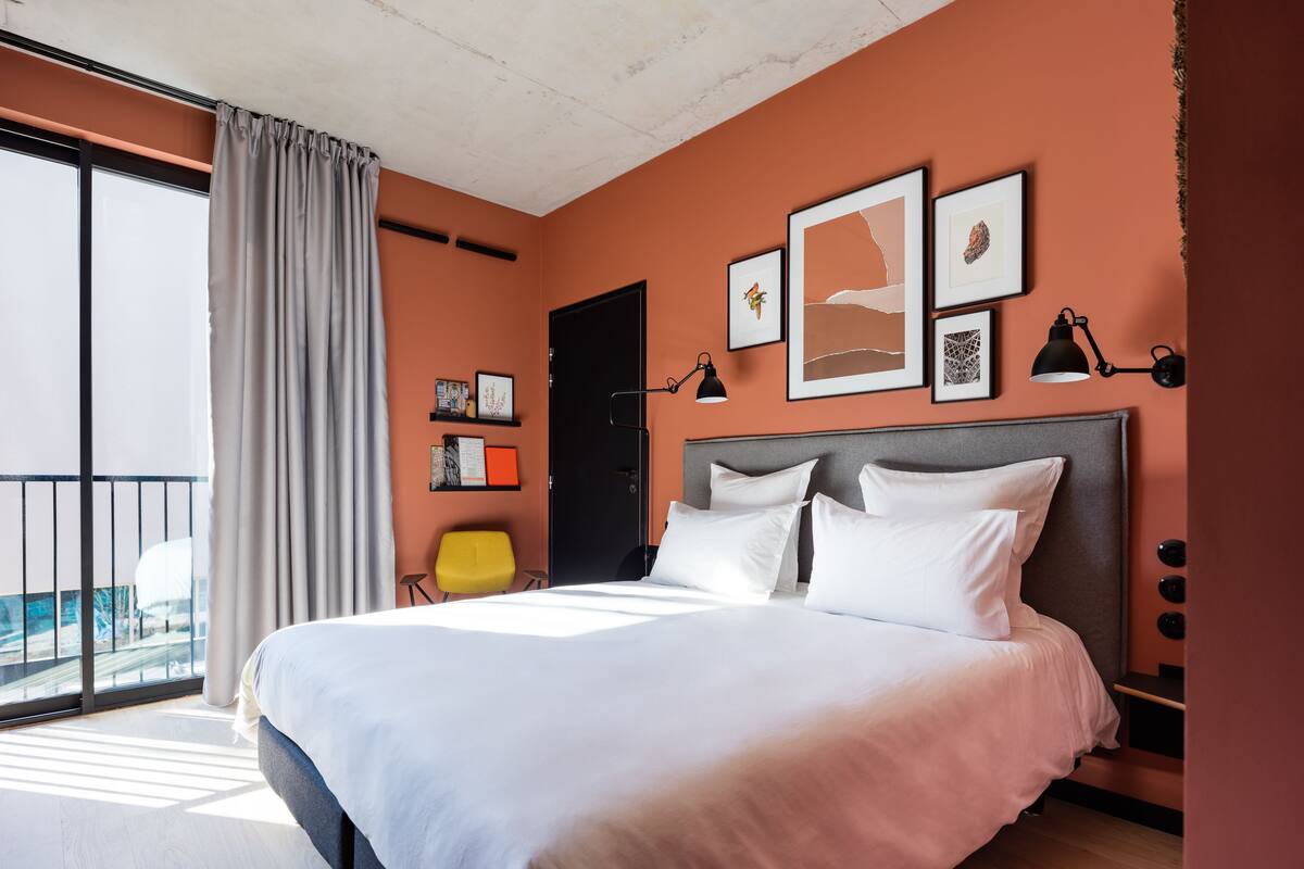 Habitación de hotel moderna con una cama grande, un balcón con vistas y obras de arte en las paredes.