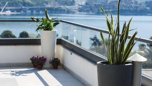 A balcony with potted plants and a view of a lake and mountains. - Boutique Hotel Arka (Budva)