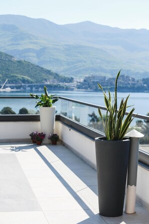 A balcony with potted plants and a view of a lake and mountains. - Boutique Hotel Arka (Budva)
