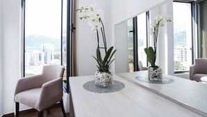 A modern room with a large window, a round table, and two potted plants. - Boutique Hotel Arka (Budva)