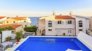 A rooftop swimming pool with a view of the sea, surrounded by buildings. - Villa Lola (Okrug)