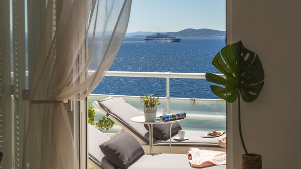 A balcony with a view of the sea, a ship in the distance, and a potted plant. - Villa Lola (Okrug)