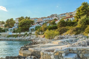 A coastal town with stone buildings, a clear sky, and a rocky shoreline. - Villa Lola (Okrug)