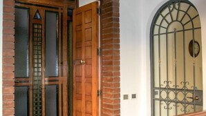 Une porte en bois avec des panneaux de verre, un portail en métal et un sol carrelé.