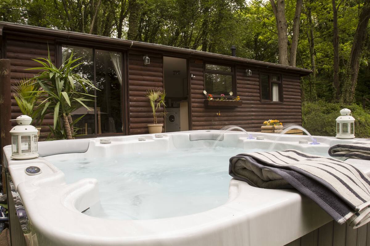 Eine Holzblockhütte mit Whirlpool davor.