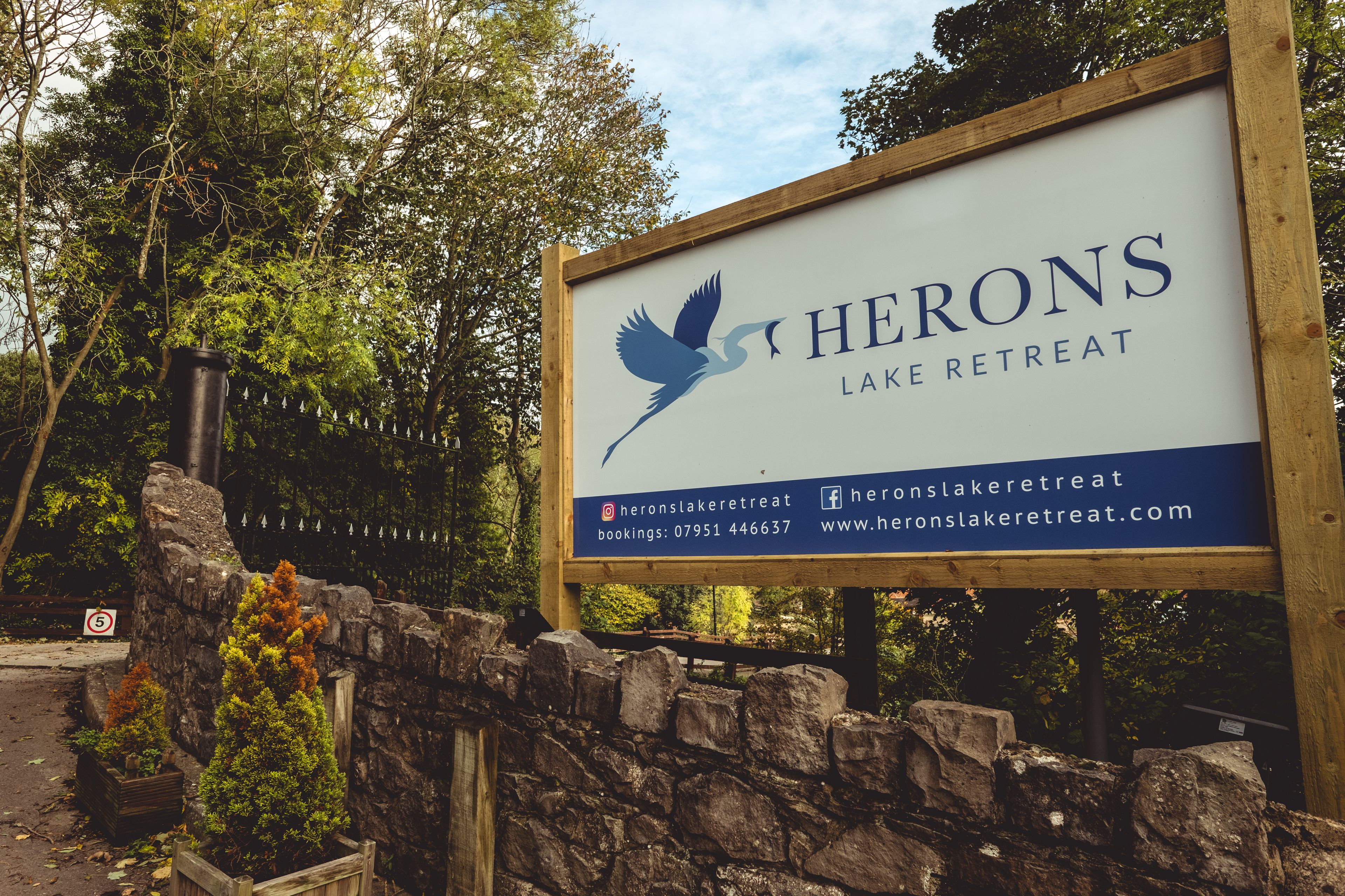 Un letrero para Herons Lake Retreat, con información de contacto y una URL de sitio web.