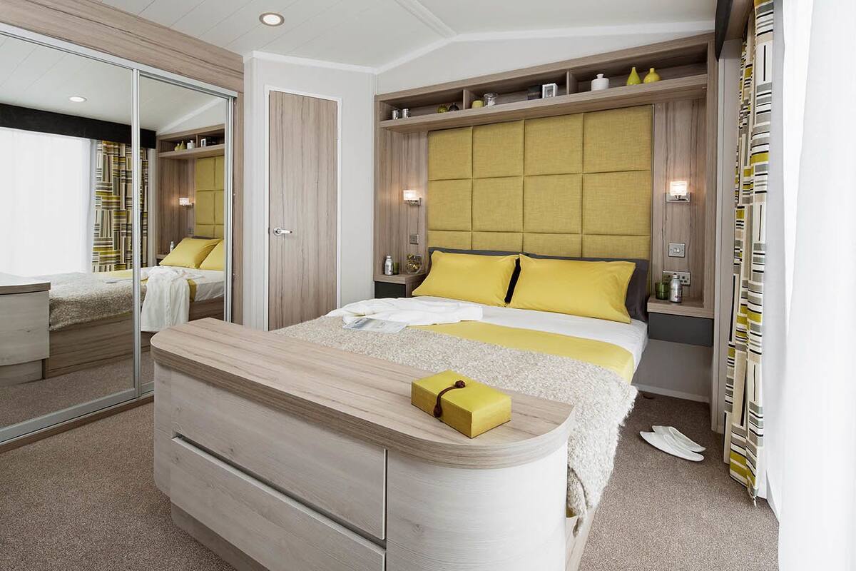 Ein modernes Schlafzimmer mit Bett, Nachttischen, einem Spiegel und einem Kleiderschrank.