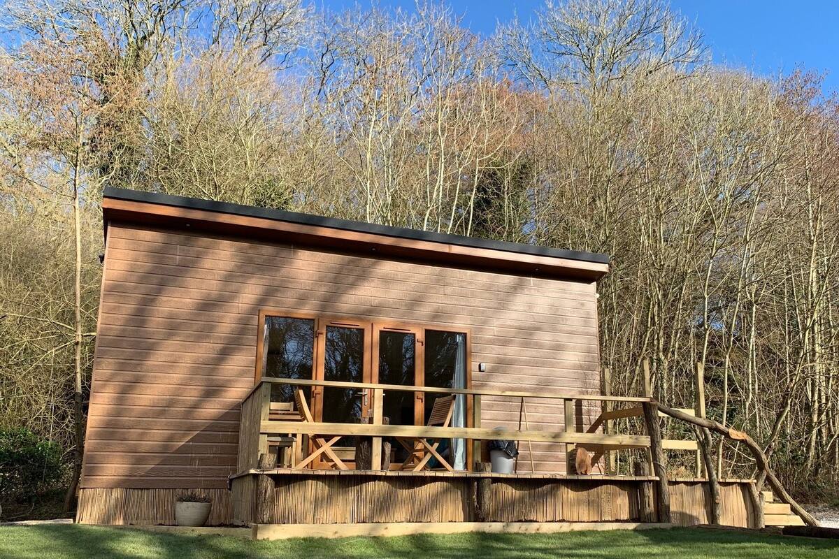 Eine kleine Holzhütte mit Balkon, umgeben von Bäumen.
