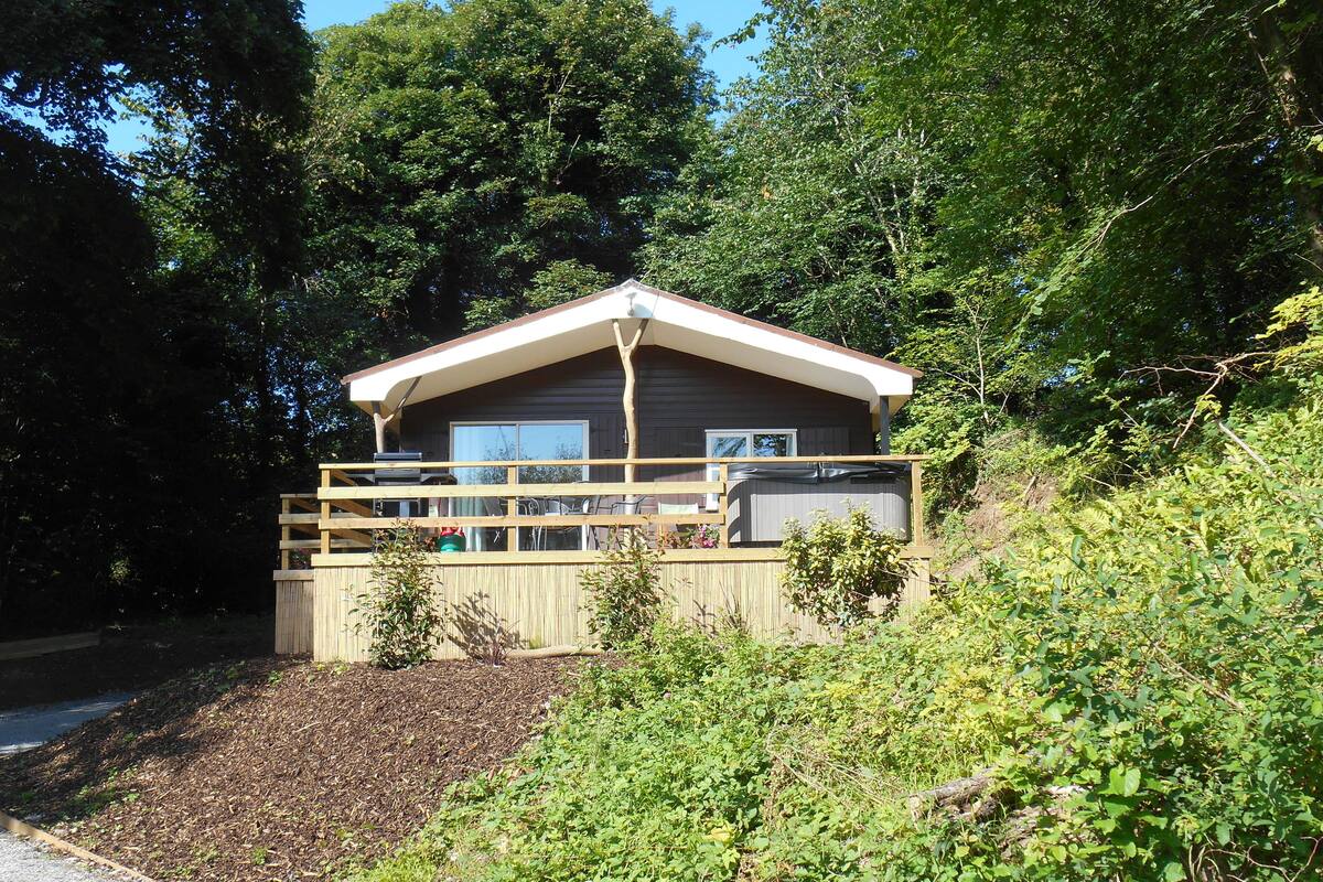 Eine Hütte mit einer Terrasse, umgeben von dichtem Grün.