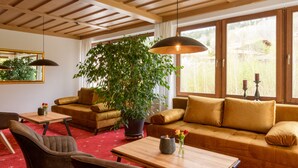 Une pièce confortable avec une grande fenêtre, un canapé, un fauteuil, une table et une plante en pot.