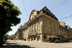Un edificio histórico con un cartel de hotel destacado, múltiples ventanas y una línea de tranvía que pasa enfrente.