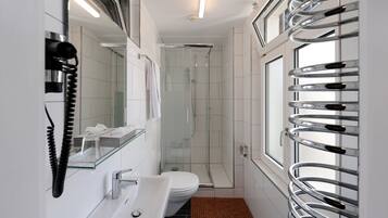 Une salle de bain moderne avec une douche à parois de verre, des toilettes, un lavabo et un téléphone fixé au mur.
