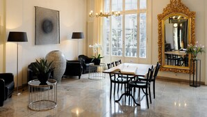 A dining area with a table, chairs, a chandelier, a large mirror, and a view of the city through the window. - Hotel National Bern (Bern)