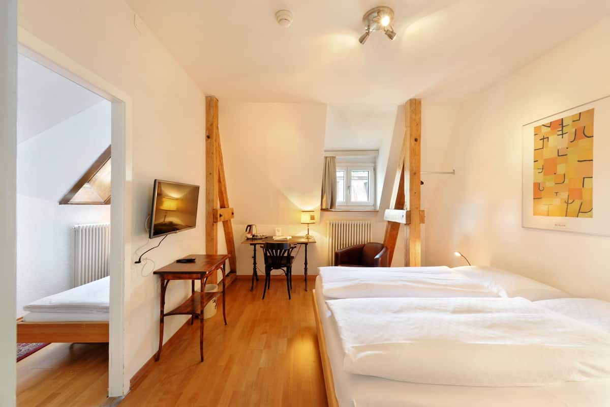 Une chambre d’hôtel avec un lit, un bureau, une chaise, une télévision et une fenêtre.