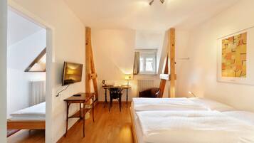 A hotel room with a bed, a desk, a chair, a TV, and a window.