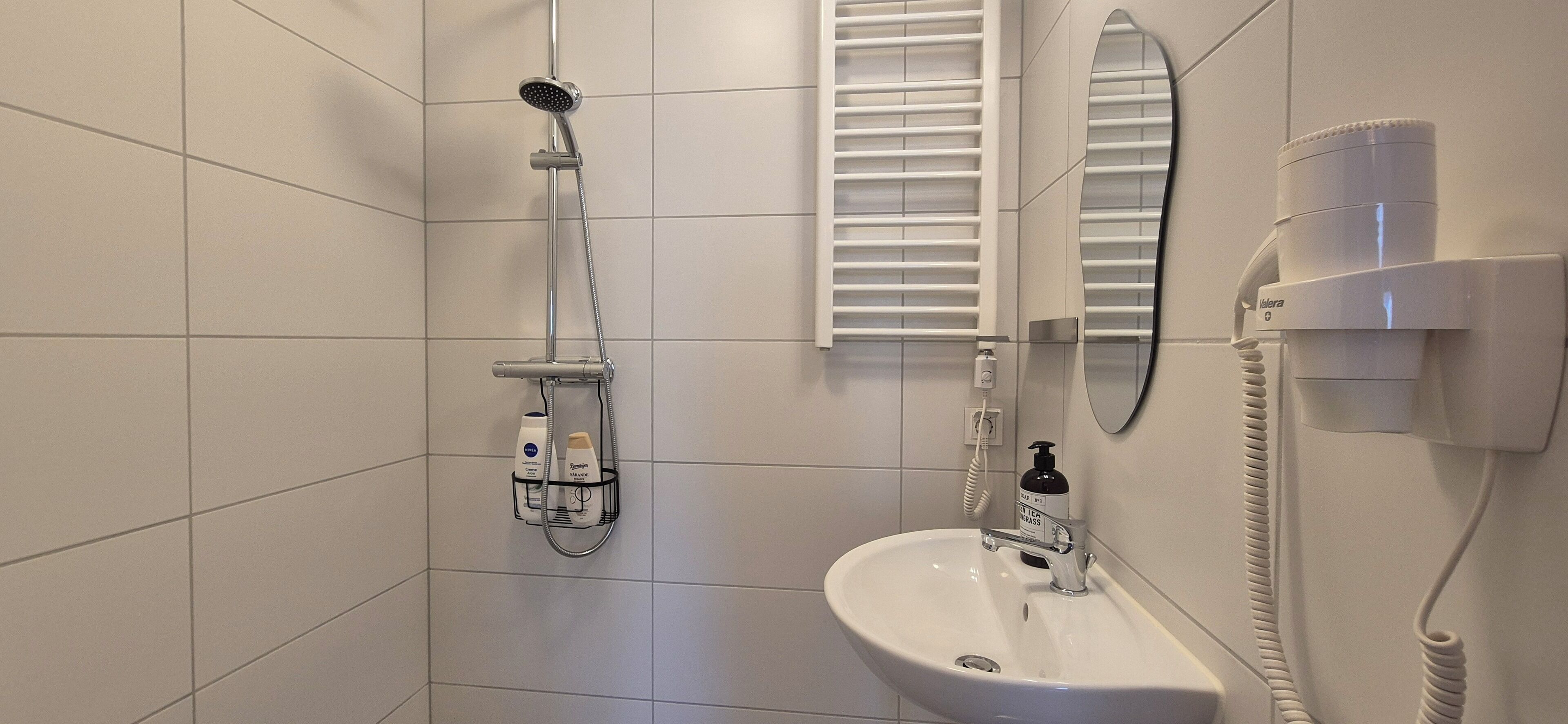 A bathroom with a shower, sink, and a mirror.