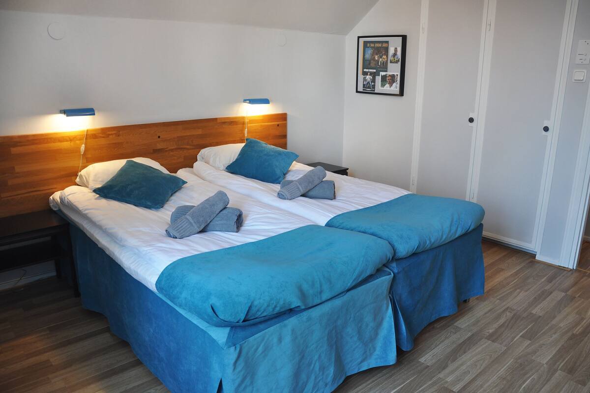 Ein Doppelbett mit Holz-Kopfteil, zwei Kissen und einer blauen Bettdecke.