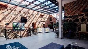 A hotel lobby with a high ceiling, exposed brick walls, and a reception desk. - Zamek Gniew - Hotel Rycerski (Gniew)
