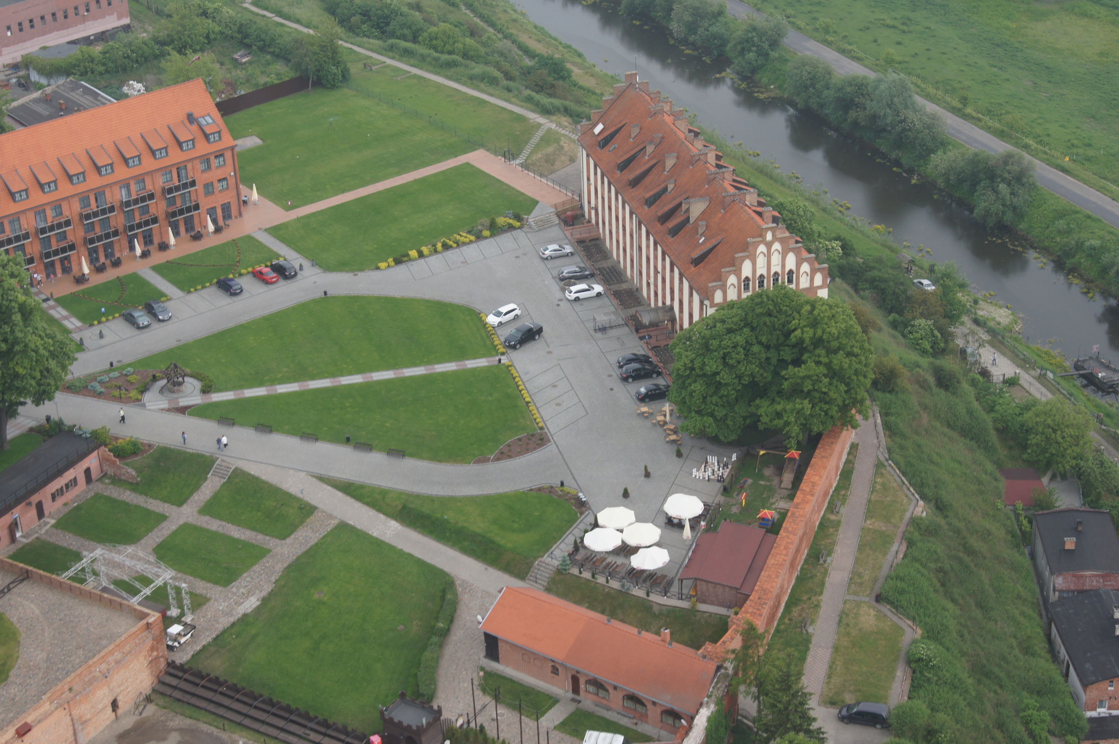 An aerial view of a campus with a large building, a parking lot, and a river.