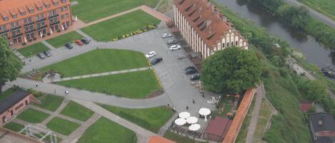 An aerial view of a campus with a large building, a parking lot, and a river.