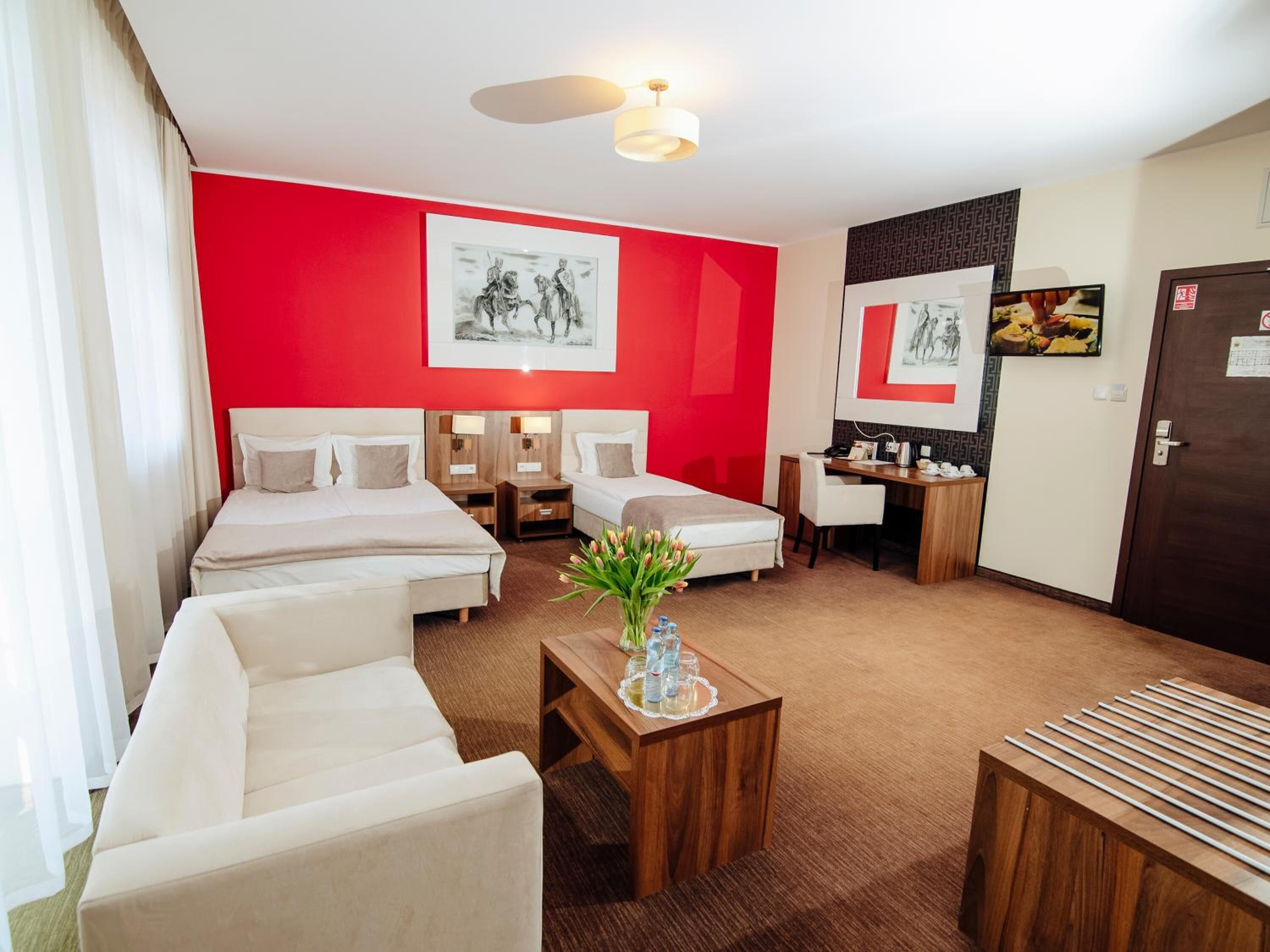Quarto de hotel com duas camas, uma escrivaninha, uma cadeira, máquina de café e obras de arte nas paredes.