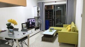 Ein modernes Wohnzimmer mit einer Couch, einem Fernseher, einem Ventilator und einem Esstisch mit Stühlen.