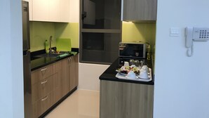 Eine kleine Küche mit einer Mikrowelle, einem Spülbecken und einer Essecke mit einer Tafel Essen.