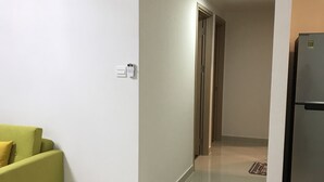 Ein modernes Wohnzimmer mit einem grünen Sofa, einem kleinen Tisch mit einer Fernbedienung und einem Kühlschrank.