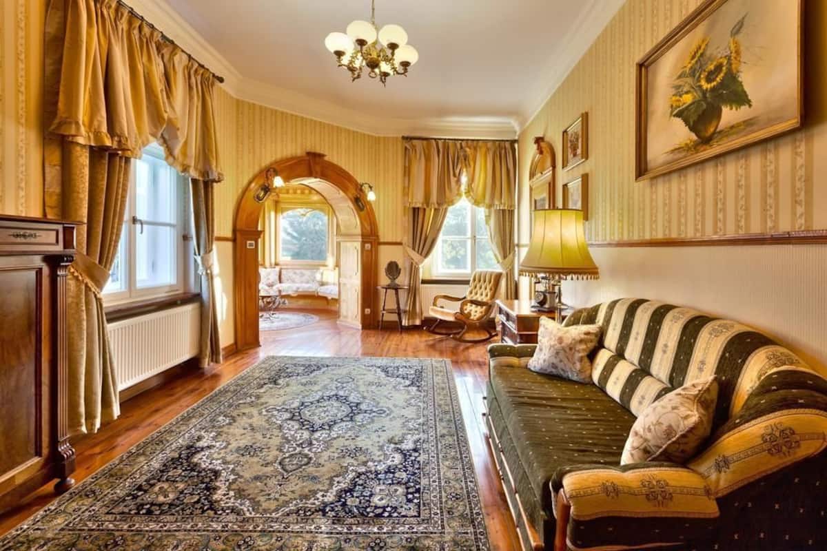 A traditional room with a sofa, a patterned rug, and a chandelier.