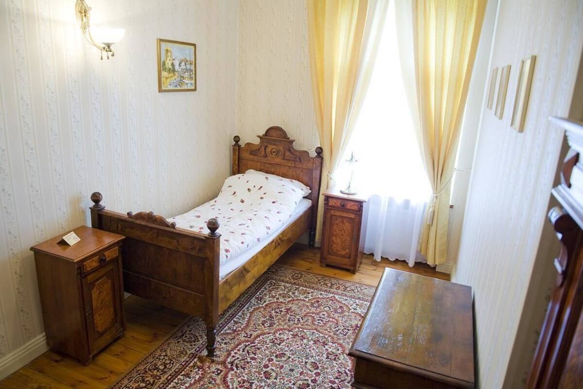 A traditional bedroom with a wooden bed, a nightstand, a bedside table, and a patterned rug.