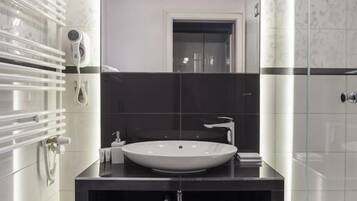 A modern bathroom with a large mirror, a white sink, and a glass shower enclosure.